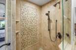 Experience luxury in this beautifully tiled shower featuring a decorative mosaic accent wall and dual shower heads for a spa-like experience.