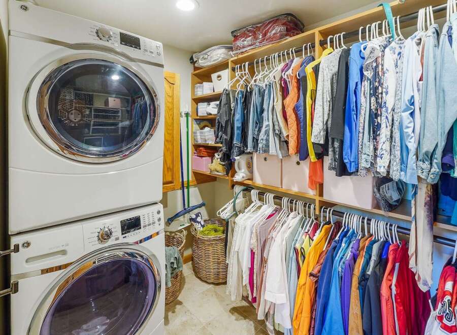 Discover this spacious walk-in closet, perfectly organized with a stacked washer and dryer unit for ultimate convenience.