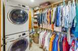Discover this spacious walk-in closet, perfectly organized with a stacked washer and dryer unit for ultimate convenience.