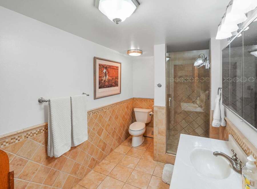 This bathroom features a tiled shower stall with glass doors, a white toilet, and a vanity with a white sink and chrome faucet.