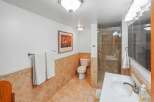 This bathroom features a tiled shower stall with glass doors, a white toilet, and a vanity with a white sink and chrome faucet.