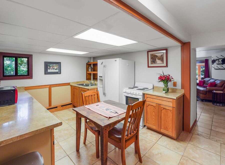 Discover this charming basement apartment featuring a compact kitchen with ample cabinet space and a dining area perfect for intimate meals.