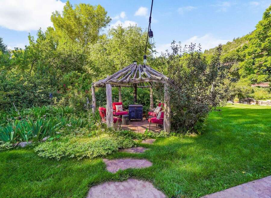 Escape to this enchanting backyard oasis, featuring a rustic wooden gazebo perfect for outdoor gatherings.
