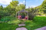 Escape to this enchanting backyard oasis, featuring a rustic wooden gazebo perfect for outdoor gatherings.