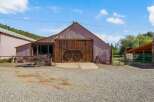 Discover this charming property featuring a rustic barn with large wooden doors, perfect for storage or conversion.