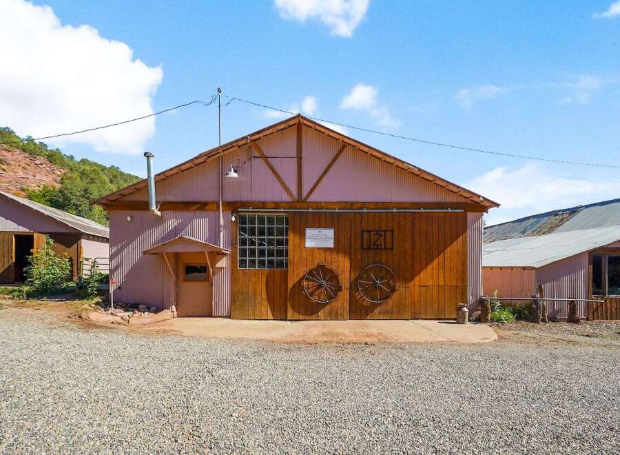 Discover this charming property featuring a rustic barn with large wooden doors and decorative wagon wheels, perfect for storage or a workshop.