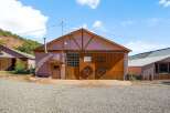 Discover this charming property featuring a rustic barn with large wooden doors and decorative wagon wheels, perfect for storage or a workshop.