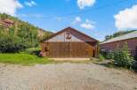 Discover this charming property featuring a rustic barn with large wooden doors, perfect for storage or housing animals.