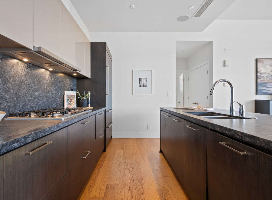 Experience modern luxury in this stunning kitchen, featuring sleek dark wood cabinetry and a dramatic dark stone backsplash.