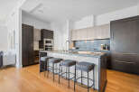 Experience modern luxury in this stunning kitchen, featuring sleek dark wood cabinetry and a spacious island with bar seating.
