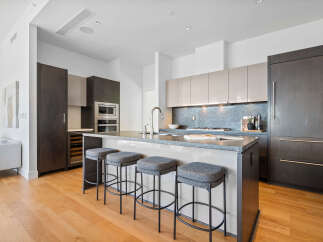 Experience modern luxury in this stunning kitchen, featuring sleek dark wood cabinetry and a spacious island with bar seating.