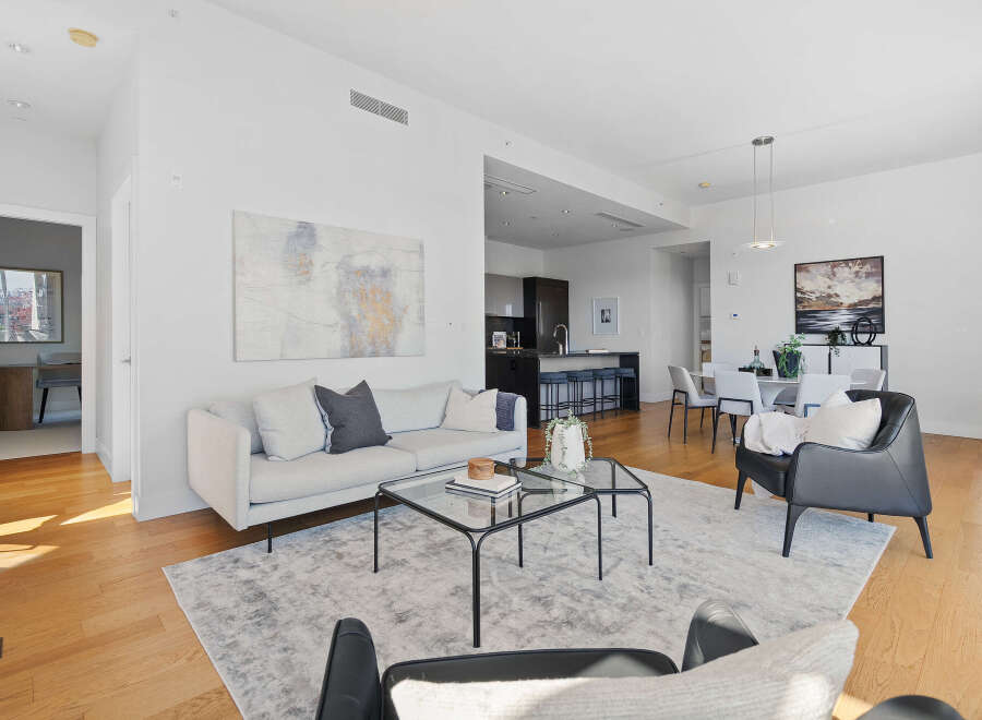 Experience modern living in this stunning open-concept space, featuring a sleek living area with a comfortable sofa and a stylish coffee table, seamlessly flowing into a contemporary kitchen with bar seating.
