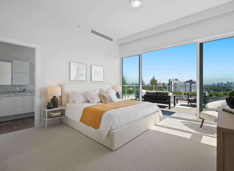 Experience luxurious urban living in this stunning master bedroom, featuring a king-sized bed with plush white linens and a vibrant ochre throw.