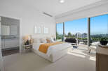 Experience luxurious urban living in this stunning master bedroom, featuring a king-sized bed with plush white linens and a vibrant ochre throw.