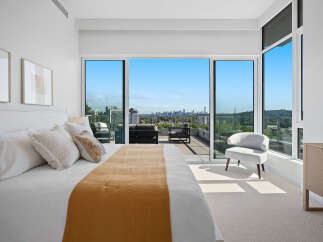 Experience luxurious urban living with this stunning bedroom featuring a king-sized bed and breathtaking panoramic city and bridge views.