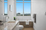 Experience luxury in this modern bathroom featuring a stunning marble vanity and a deep soaking tub with a breathtaking city view.