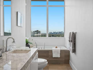 Experience luxury in this modern bathroom featuring a stunning marble vanity and a deep soaking tub with a breathtaking city view.