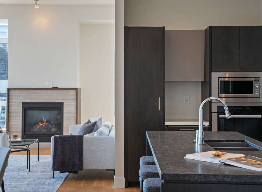 Experience modern living in this stunning open-concept space, featuring a cozy fireplace and a sleek, contemporary kitchen.