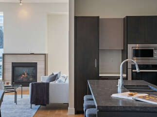 Experience modern living in this stunning open-concept space, featuring a cozy fireplace and a sleek, contemporary kitchen.