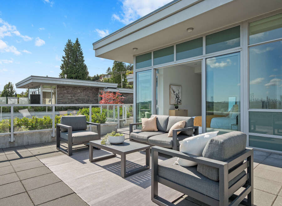 Experience luxurious outdoor living on this expansive patio, featuring a modern seating area with plush cushions and a stylish coffee table.