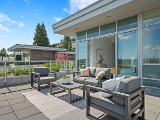 Experience luxurious outdoor living on this expansive patio, featuring a modern seating area with plush cushions and a stylish coffee table.