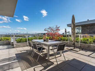 Enjoy breathtaking city and water views from this expansive rooftop patio, perfect for al fresco dining and entertaining.