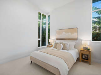 Experience modern living in this serene bedroom, featuring a plush bed adorned with decorative pillows and a neutral throw.