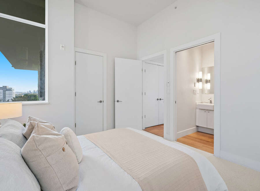 Experience modern living in this bright bedroom featuring a large window with city views and an en-suite bathroom.