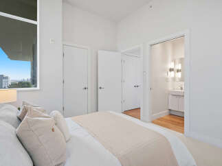 Experience modern living in this bright bedroom featuring a large window with city views and an en-suite bathroom.