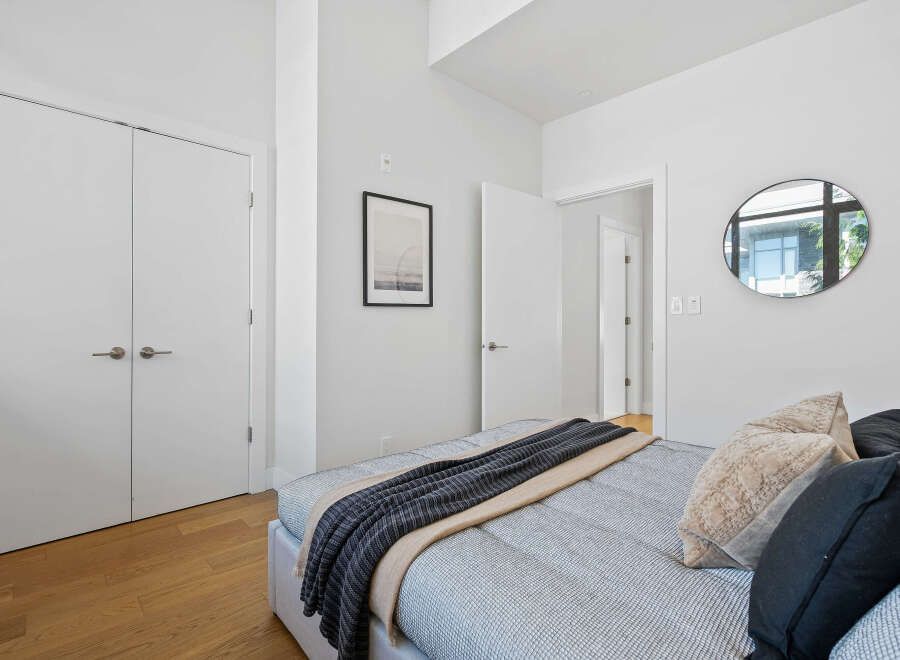 Experience modern comfort in this bright bedroom, featuring a plush bed adorned with a stylish throw and accent pillows.