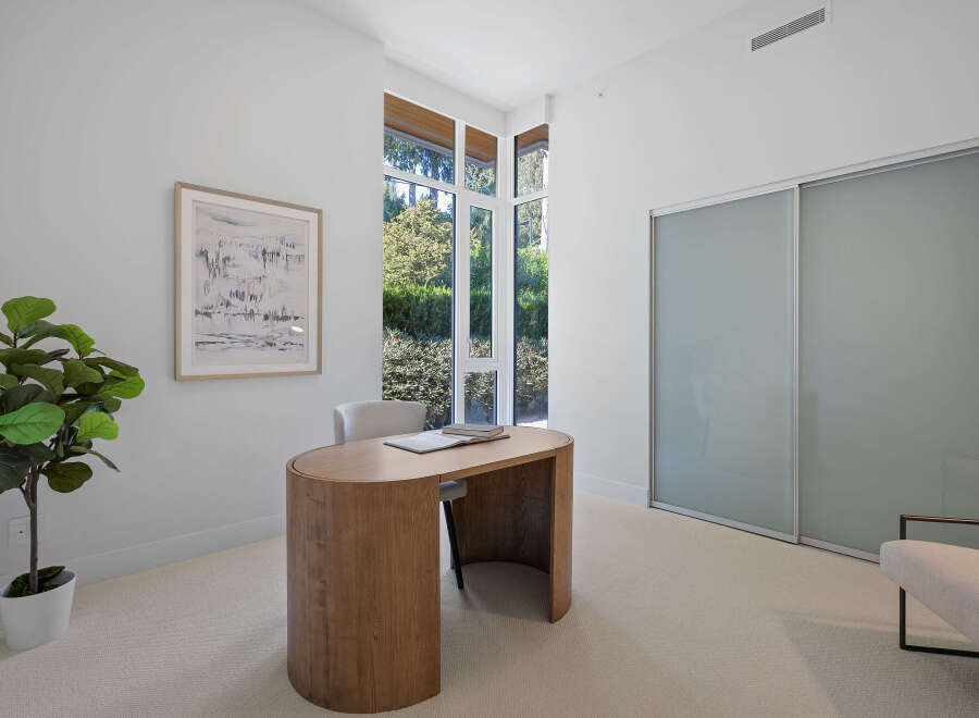 This modern home office features a sleek, curved wooden desk complemented by a comfortable upholstered chair.