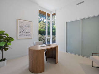 This modern home office features a sleek, curved wooden desk complemented by a comfortable upholstered chair.