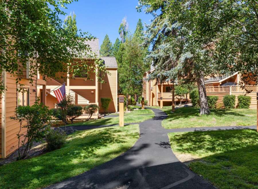 Discover this charming property featuring warm, wood-sided buildings nestled amongst mature trees and lush green lawns.