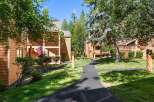 Discover this charming property featuring warm, wood-sided buildings nestled amongst mature trees and lush green lawns.