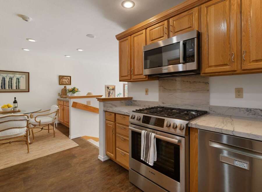 This kitchen features modern stainless steel appliances, including a Bosch gas range and microwave, complemented by elegant marble countertops and backsplash.