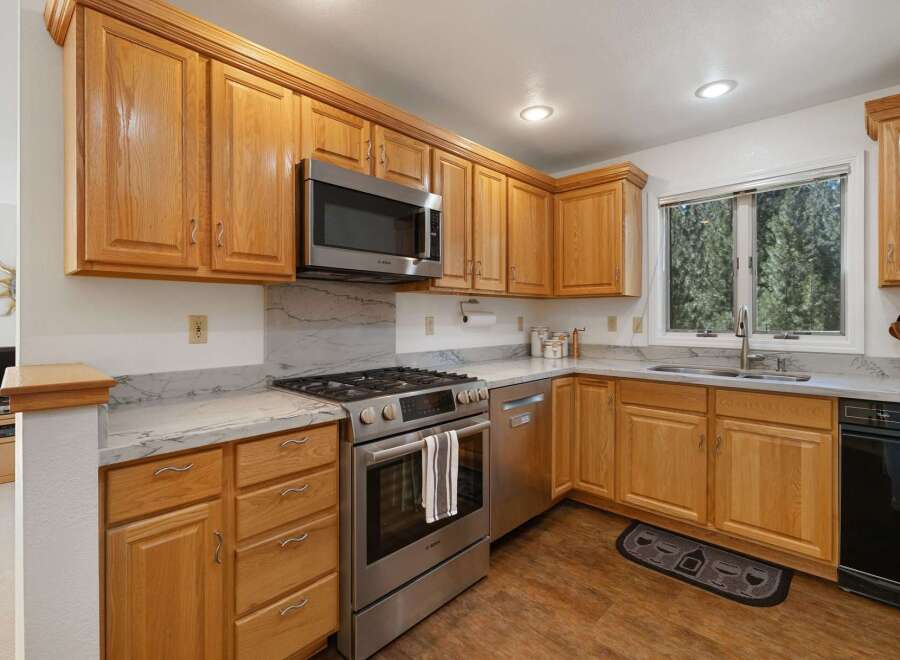 This kitchen boasts beautiful natural wood cabinetry, complemented by sleek stainless steel appliances including a microwave and a modern gas range.