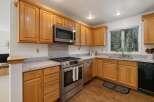 This kitchen boasts beautiful natural wood cabinetry, complemented by sleek stainless steel appliances including a microwave and a modern gas range.