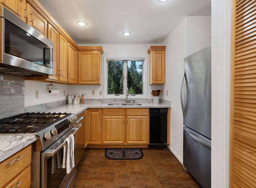 This charming kitchen features warm oak cabinetry complemented by sleek stainless steel appliances, including a gas range and microwave.