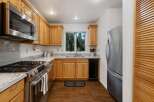 This charming kitchen features warm oak cabinetry complemented by sleek stainless steel appliances, including a gas range and microwave.
