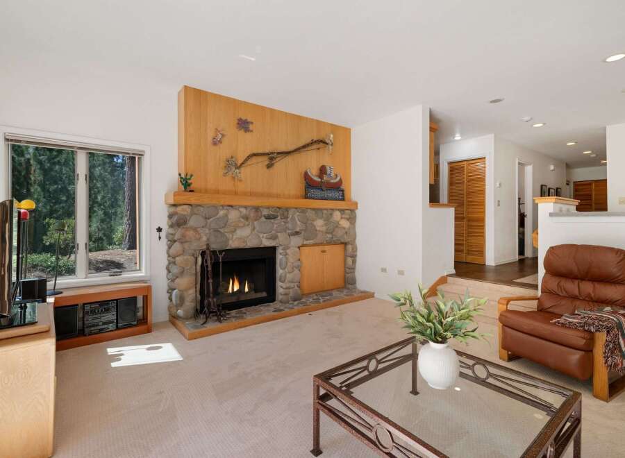 Cozy living room featuring a natural stone fireplace with a rustic wooden mantel, perfect for gathering on cool evenings.