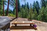 Enjoy the serene mountain lifestyle with this charming outdoor seating area, perfect for relaxing amidst the tall pine trees.