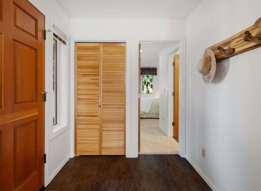 Welcome guests into this charming entryway featuring a warm wooden door and convenient louvered closet doors.