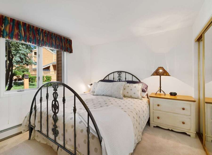 This charming bedroom features a comfortable queen-size bed with a decorative metal headboard, perfect for a restful night's sleep.