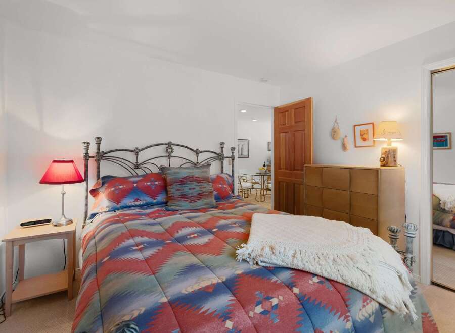 Experience comfort and style in this inviting bedroom, featuring a striking metal-frame bed adorned with a vibrant, patterned comforter.