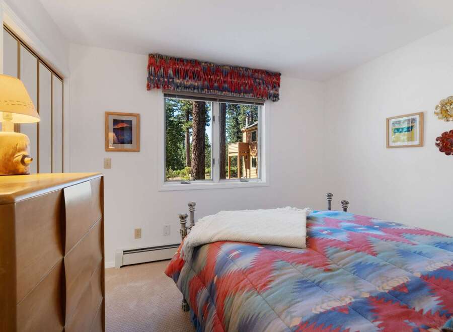 This charming bedroom features a cozy bed adorned with a vibrant, patterned comforter and a plush throw.