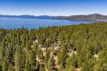Nestled amidst a dense forest of evergreen trees, this property offers a serene retreat with stunning views of a vast blue lake and distant snow-capped mountains.