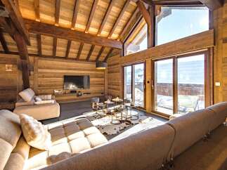 Experience luxury mountain living in this stunning chalet featuring a spacious open-plan living area with a modern entertainment setup and comfortable seating.