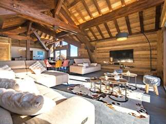 Experience luxury mountain living in this stunning chalet featuring a spacious open-plan living area with exposed wooden beams and a cozy fireplace.