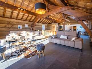 Experience rustic luxury in this stunning chalet living room, featuring exposed wooden beams and a vaulted ceiling.
