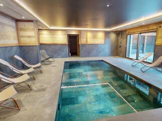 Indulge in ultimate relaxation in this luxurious indoor swimming pool area, featuring a stunning turquoise tiled pool.
